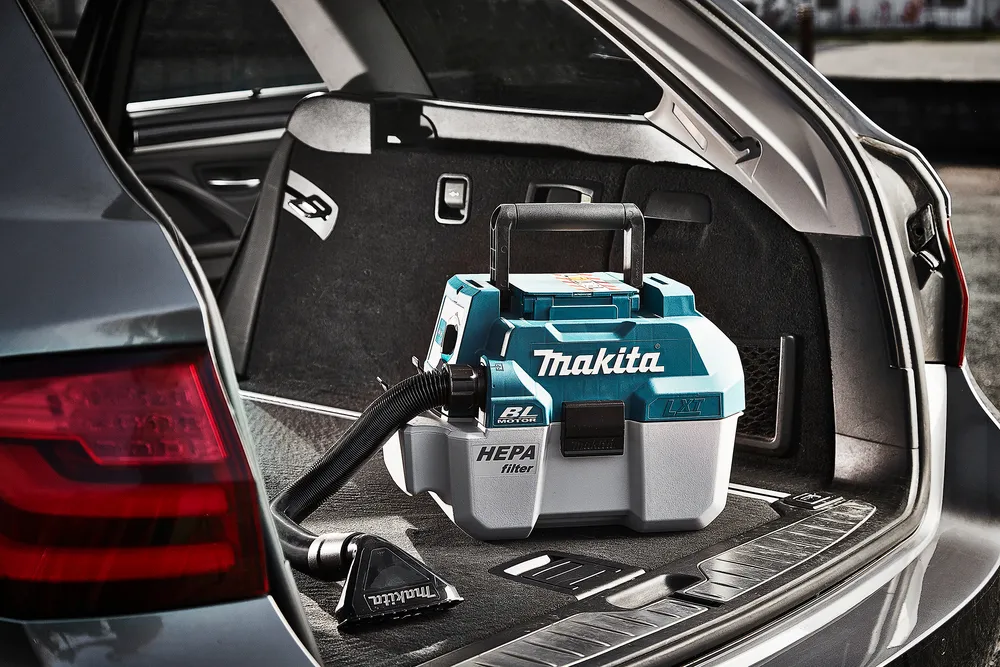 Pildil on Makita akuga vee- ja tolmuimeja DVC750LZ, mis on paigutatud autotööriistadele autosse.