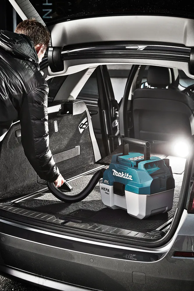 Pildil on Makita akuga vee- ja tolmuimeja, mida kasutatakse auto pagasiruumi puhastamiseks.
