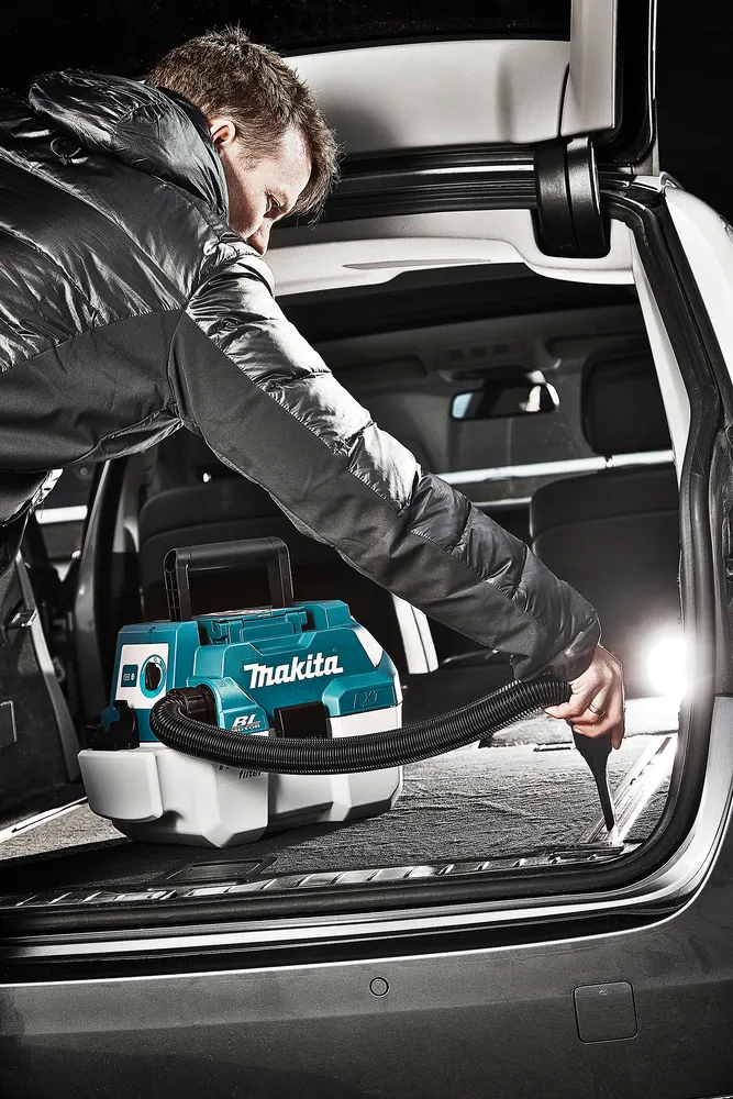 Pildil on näha mees kasutamas Makita akuga vee- ja tolmuimejat DVC750LZ auto pagasiruumi puhastamiseks.