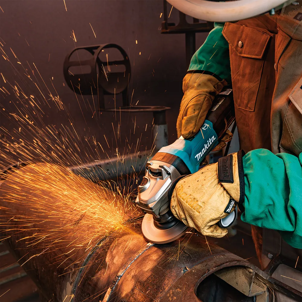 Pildil on näha Makita nurklihvija GA5093X01, mida kasutatakse metalltoru lihvimiseks, mille käigus tekivad sädemed.