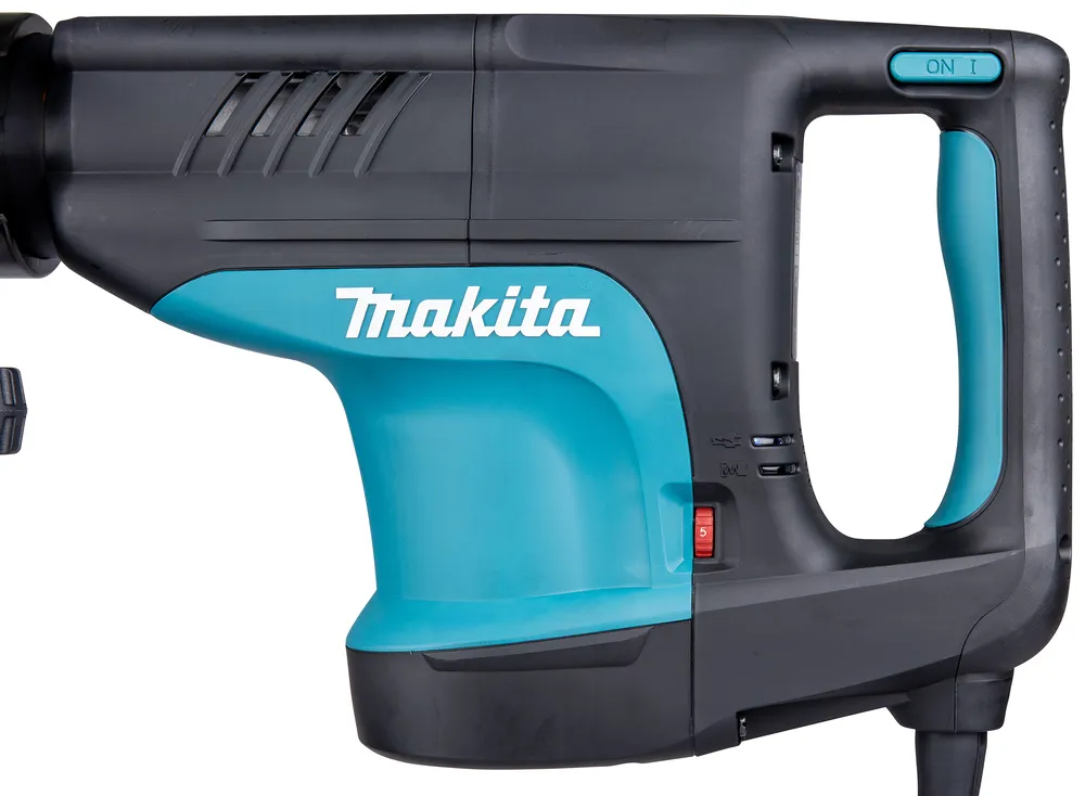 Pildil on detailne vaade Makita piikvasara HM1203C korpusest, näidates tööriista siniseid ja musti detaile ning Makita logo.
