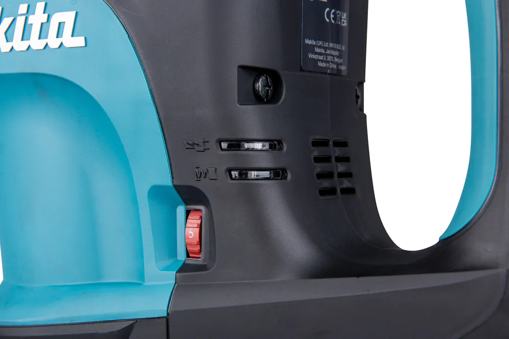 Pildil on detailid Makita piikvasar HM1203C-st, näidates toote külge koos lülitite ja sätetega.