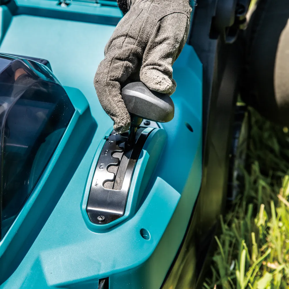 Pildil on Makita akumuruniiduk LM004GM103, XGT, mille juures inimene reguleerib niidukit.