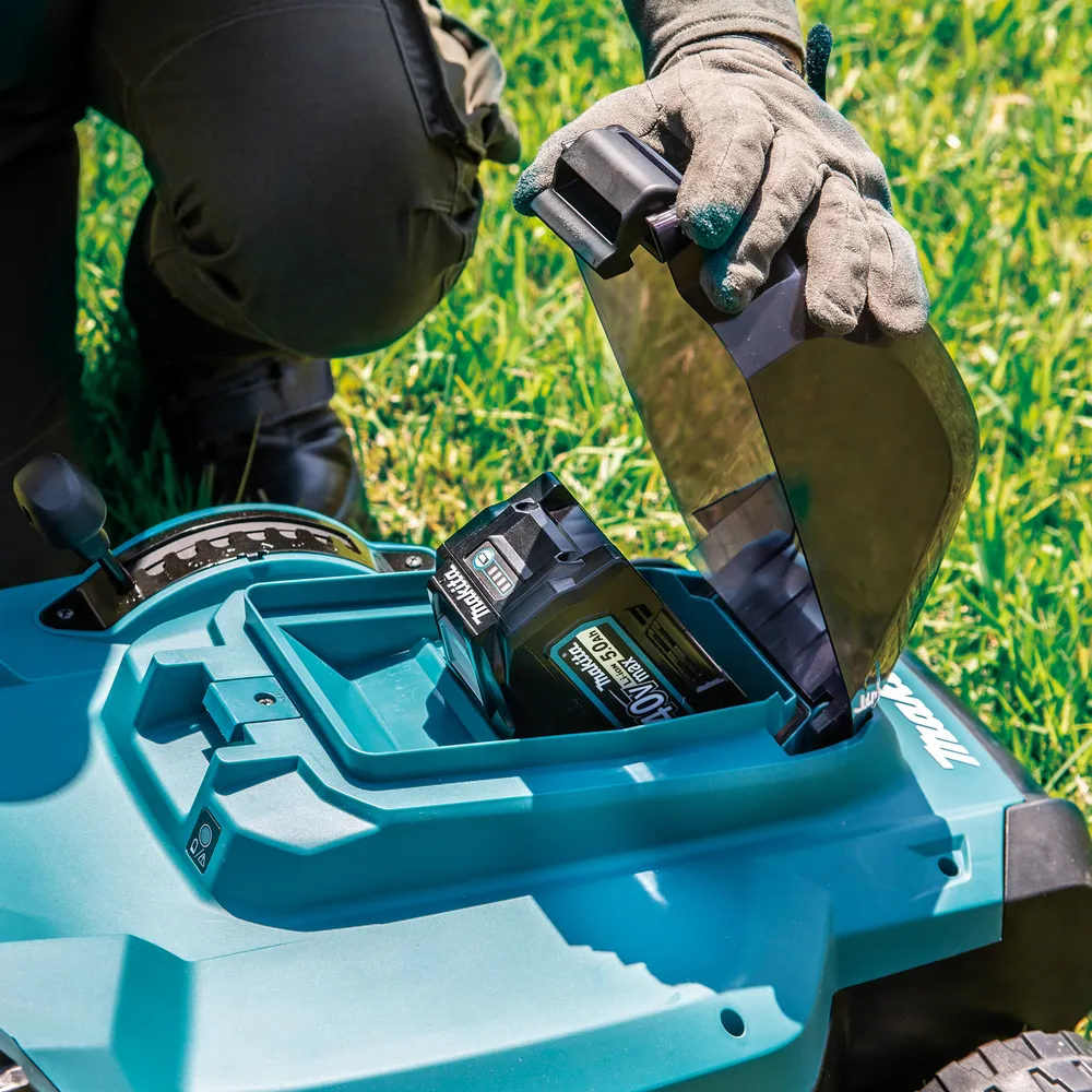 Pildil on näha Makita akumuruniiduk LM004GM103, XGT, millele inimene paigaldab akut.