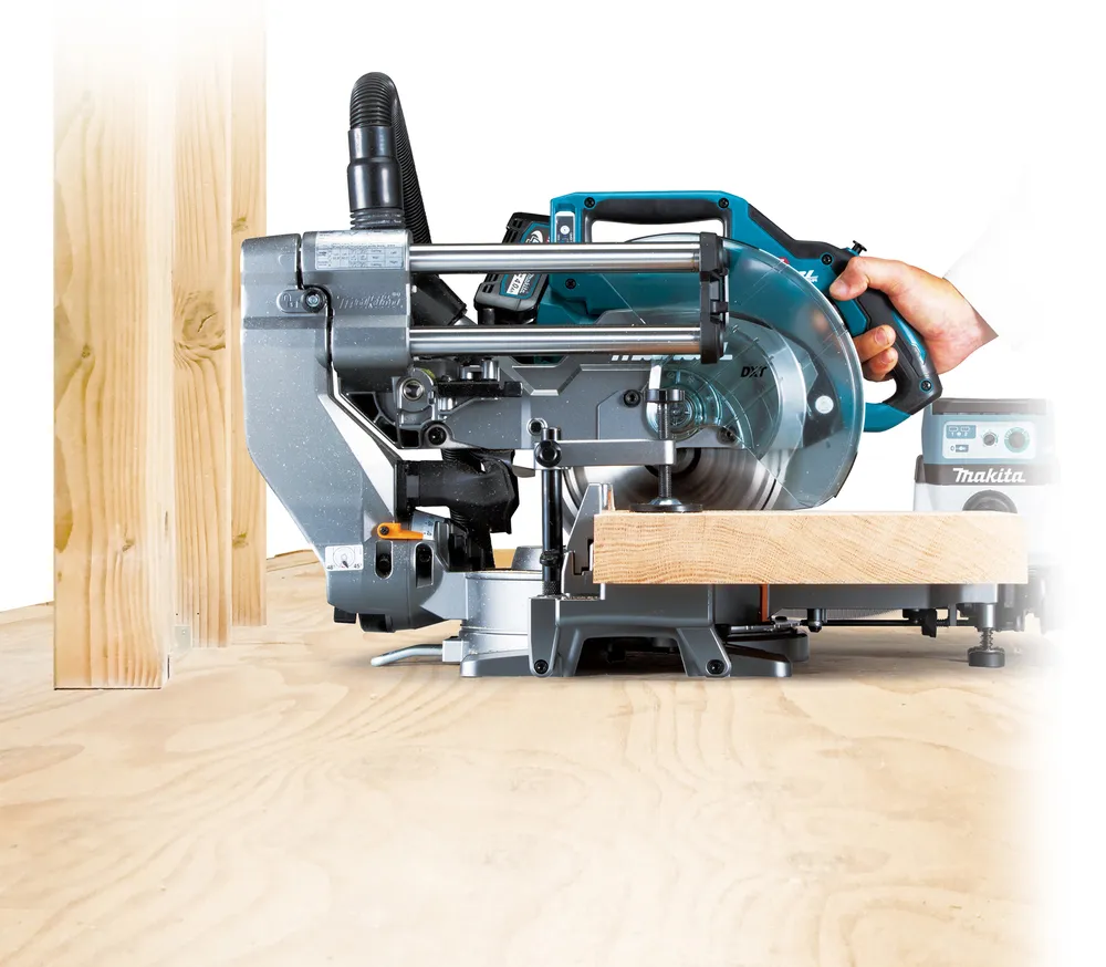 Pildil on Makita akuga tükeldus- ja nurksaag LS002GZ01, millega on lõikamas puitu.