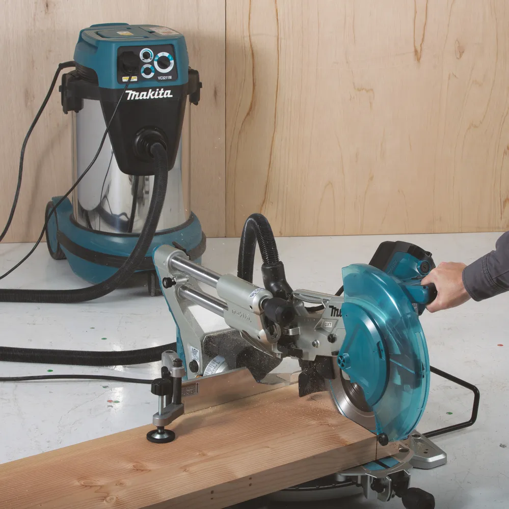 Pildil on näha Makita tükeldus- ja nurksaag LS1019L koos tolmuimejaga, mida kasutatakse puidu töötlemiseks.