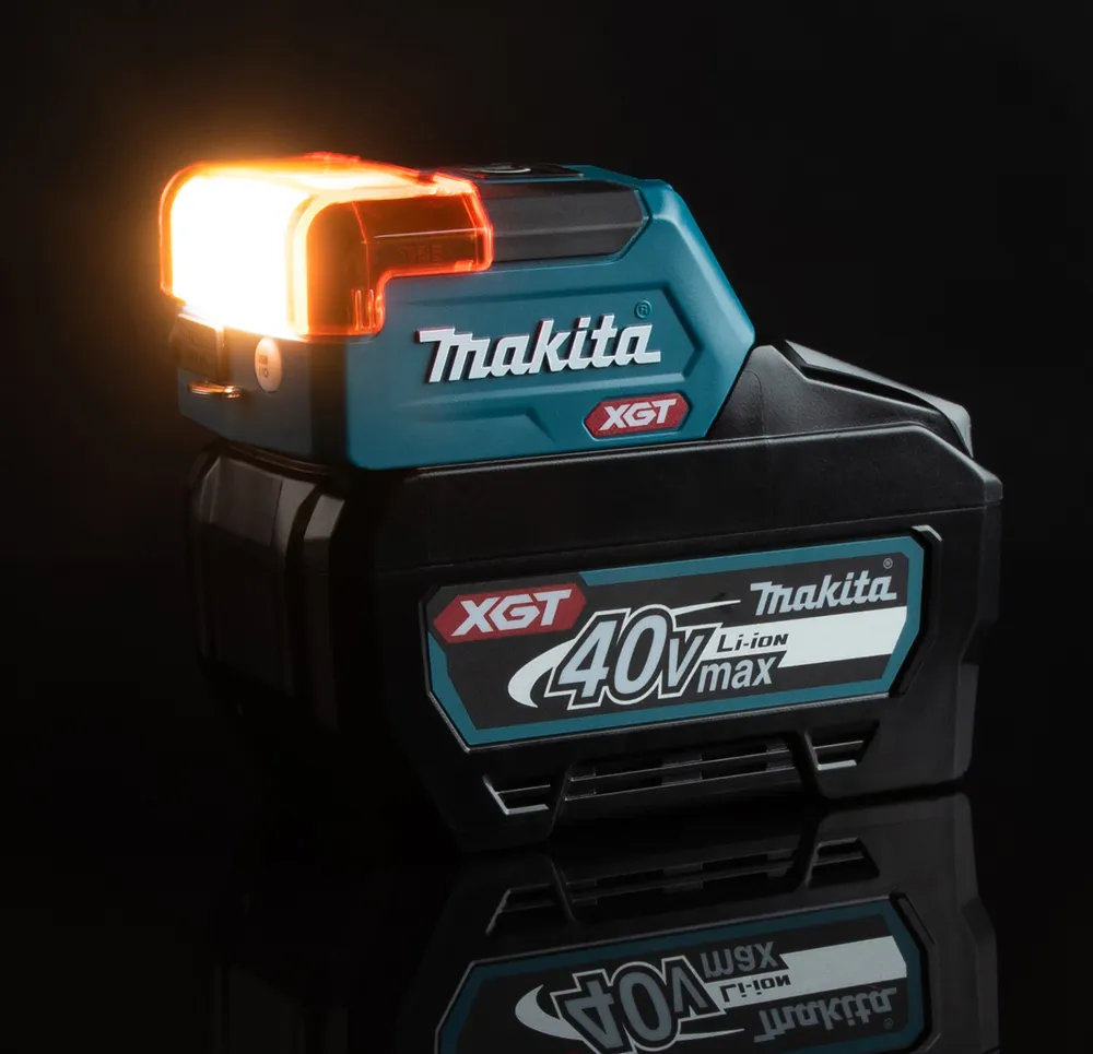 Pildil on näha Makita akulamp ML011G, mis on valgustatud eredalt, koos all oleva 40V XGT Li-ion akuga, millel on peal...