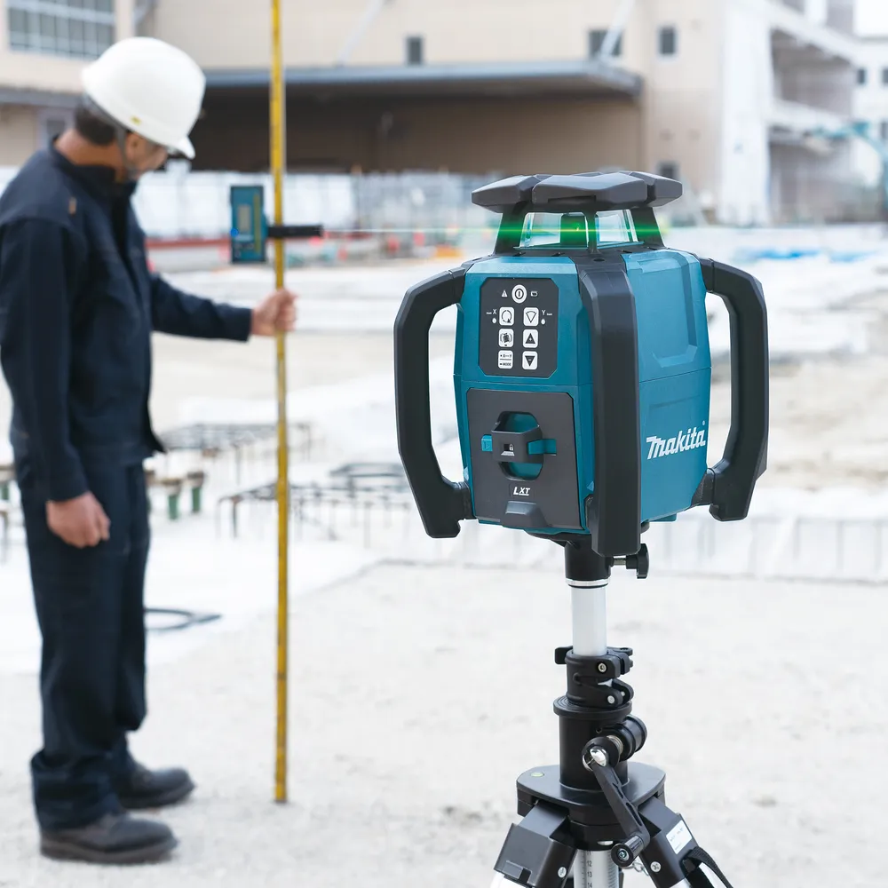 Pildil on Makita akupöördlaser SKR001Z, mis on kinnitatud statiivile ja mida kasutab töömees ehitusplatsil.