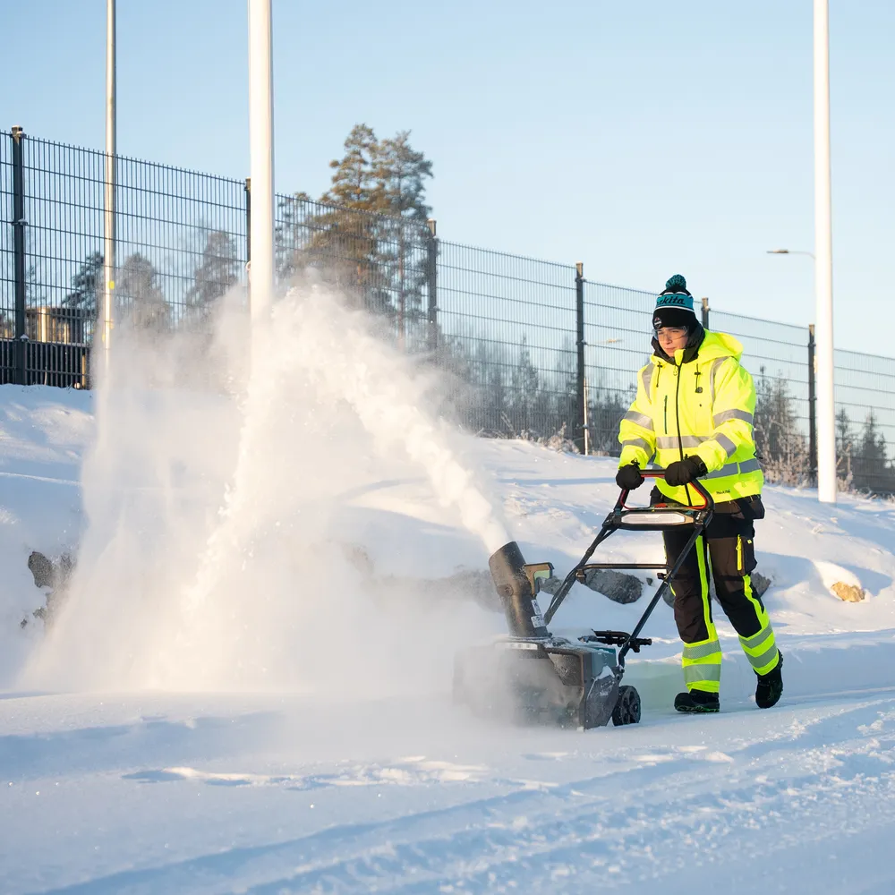 Pildil on mees, kes kasutab Makita akulumepuhurit SN001GZ, et lund eemaldada.