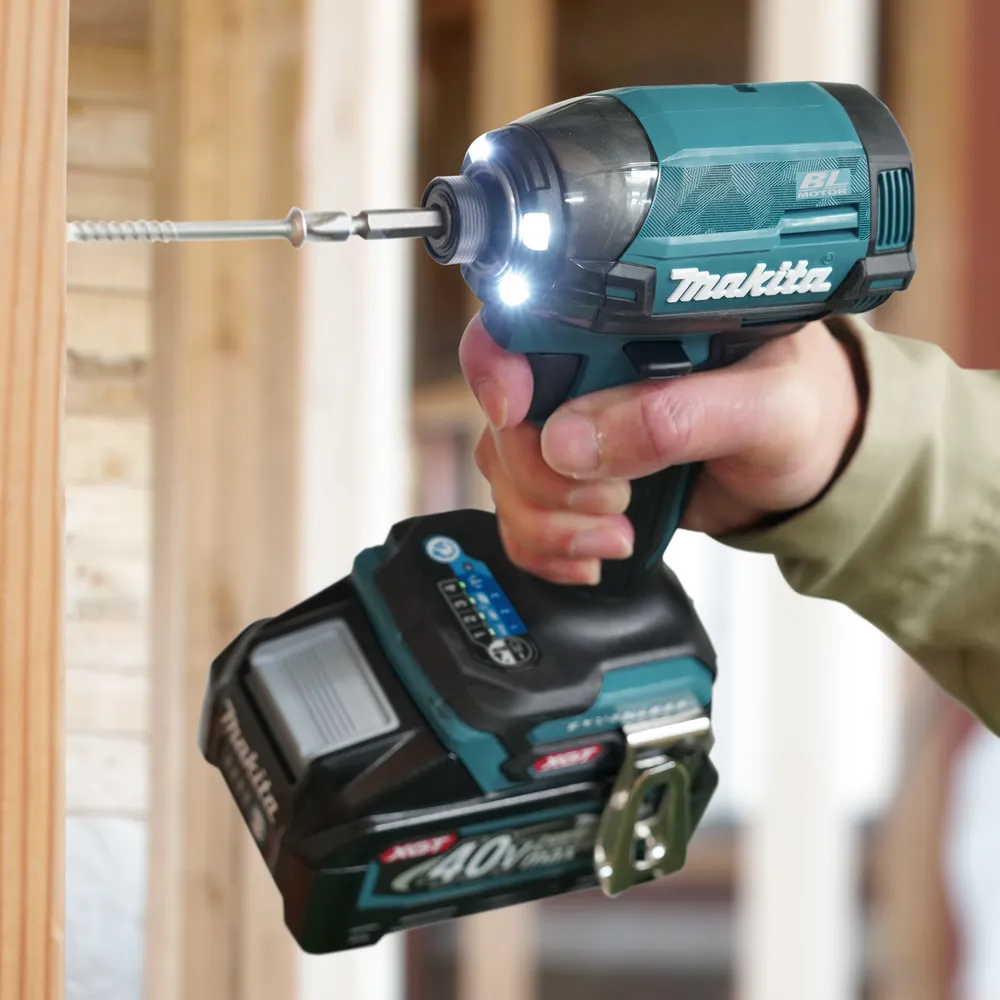 Pildil on Makita akulöökkruvikeeraja TD002GZ01, mis on käes ja töötab, keerates kruvi puidust pinnale.