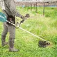 Pildil on näha inimene, kes kasutab Makita akutoitel võsa- ja rohulõikurit UR012GZ06, XGT, ilma aku ja laadijata, et...