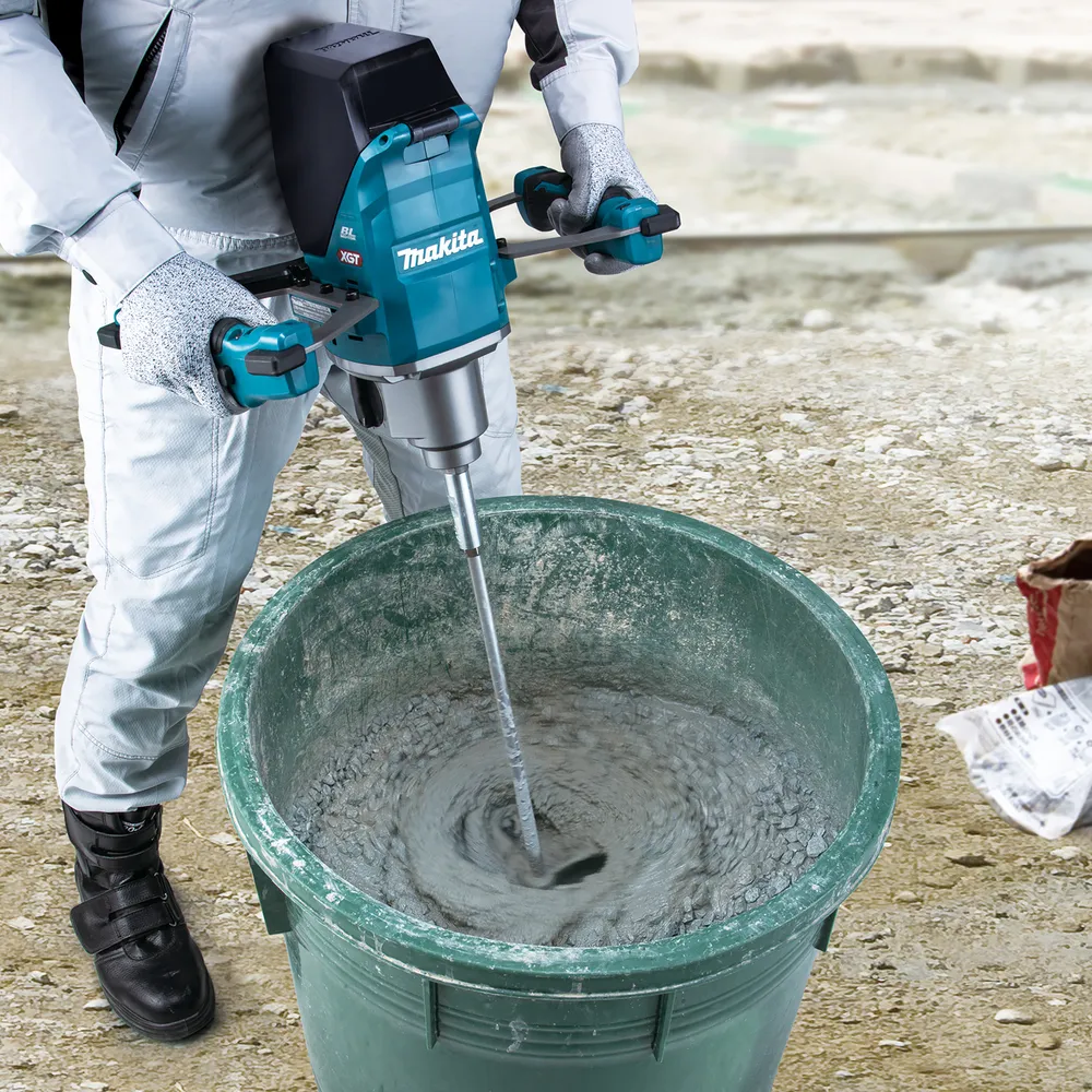 Pildil on Makita akusegutrelliga UT001GM102 segamas betooni suures rohelises ämbris.