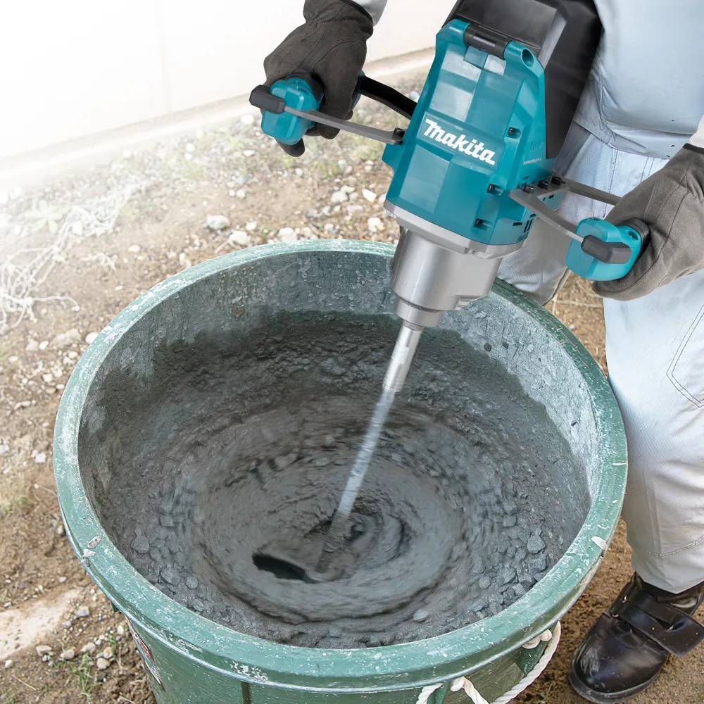 Pildil on näha Makita akusegutrell UT001GM102, mida kasutatakse betooni segamiseks suures rohelises ämbris.