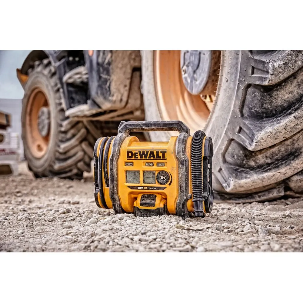 Pildil on kollane Dewalt akutoitel kompressor DCC018N, mis asetseb kruusal suure ratta kõrval.