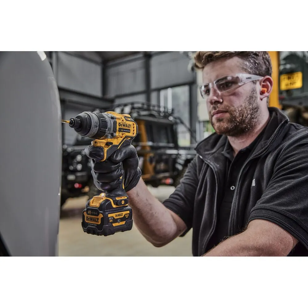Pildil on näha DeWalt akutrelli DCD703NT, millega meestöötaja puurib seina.