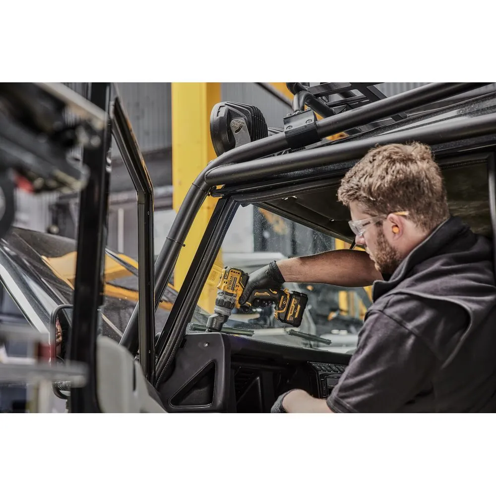 Pildil on töömees, kes kasutab Dewalt akutrelli DCD703NT, et teha tööd Defenderi autol.