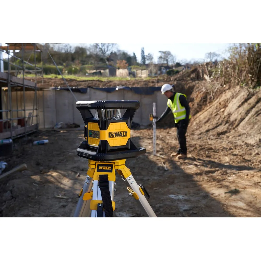 Pildil on näha DeWalt pöördlaser DCE074D1R paigaldatuna statiivile ehitusobjektil, kus töötab ehitusmees.