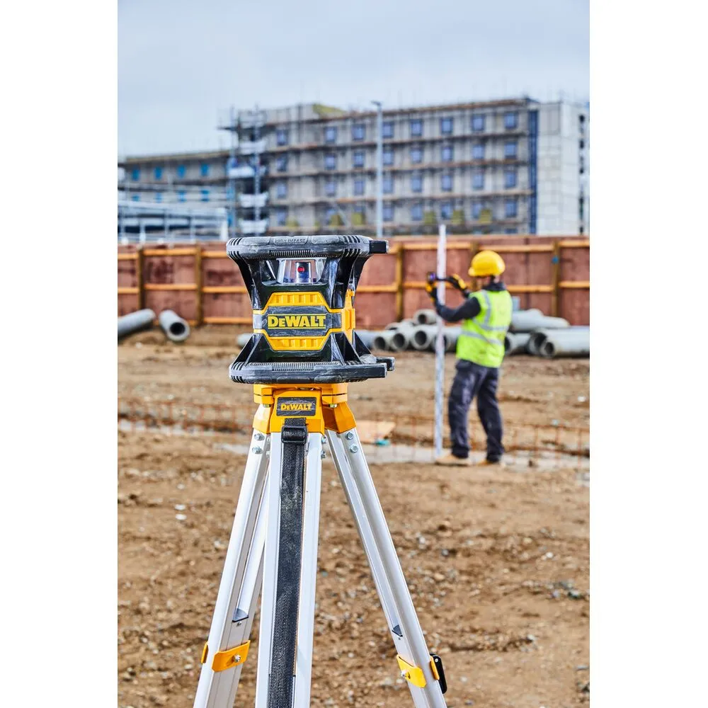 Pildil on näha DeWalt pöördlaser DCE080D1RS tööriist ehitusplatsil, mille taustal töötaja kasutab taseme mõõtmiseks.