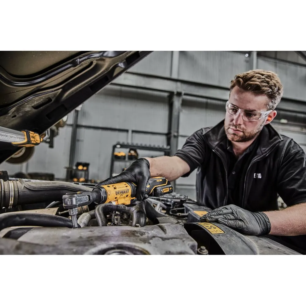 Pildil on näha professionaal, kes kasutab DeWalt 3/8" akuratretti DCF503L1G auto mootori juures.
