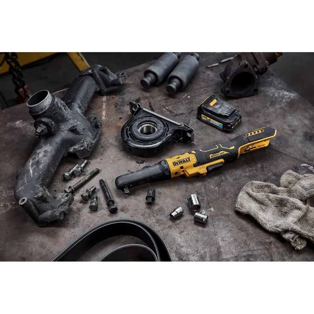 Pildil on näha DeWalt DCF510E2G akulöökkruvikeeraja koos erinevate autoosade ja tööriistadega töölaual.