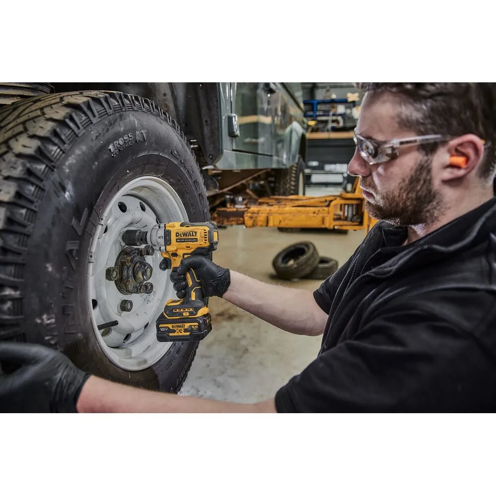 Pildil on mees, kes kasutab DeWalt akulöökmutrikeerajat, et vahetada autotalli töökojas auto ratast.