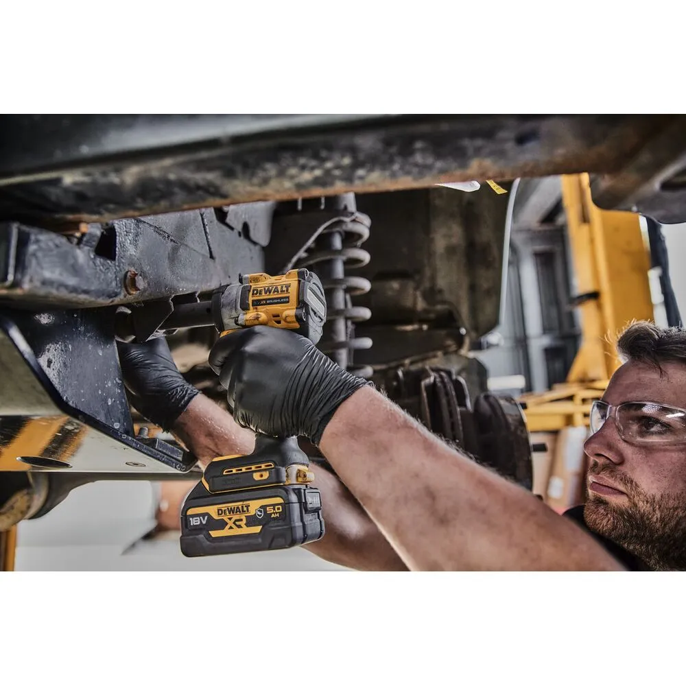 Pildil on mees, kes kasutab DeWalt akulöökmutrikeerajat sõiduki all auto remonditöökojas.