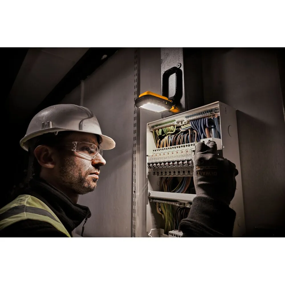 Pildil näeb elektritööline DeWalt laetavat USB-C LED töövalgustit kasutamas ja elektrikilpi paigaldamas.