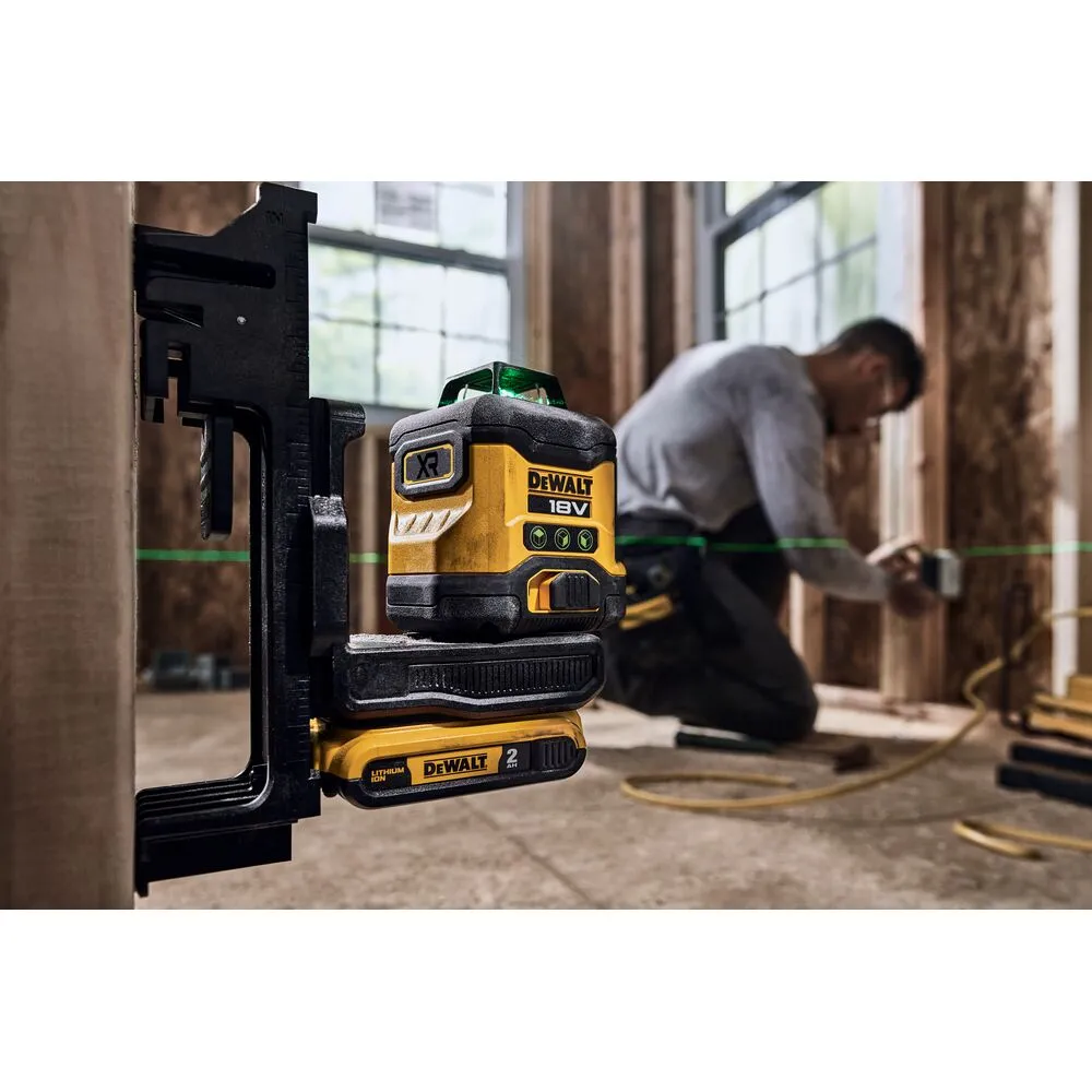 Pildil on näha DeWalt ristlaser, mis on kinnitatud musta kronsteini külge, mille taustal mees töötab.