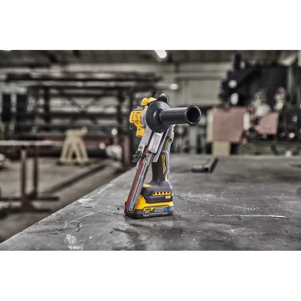 Pildil on DeWalt akulintlihvija DCM200E2T, mis on paigutatud töölauale tehase taustal.