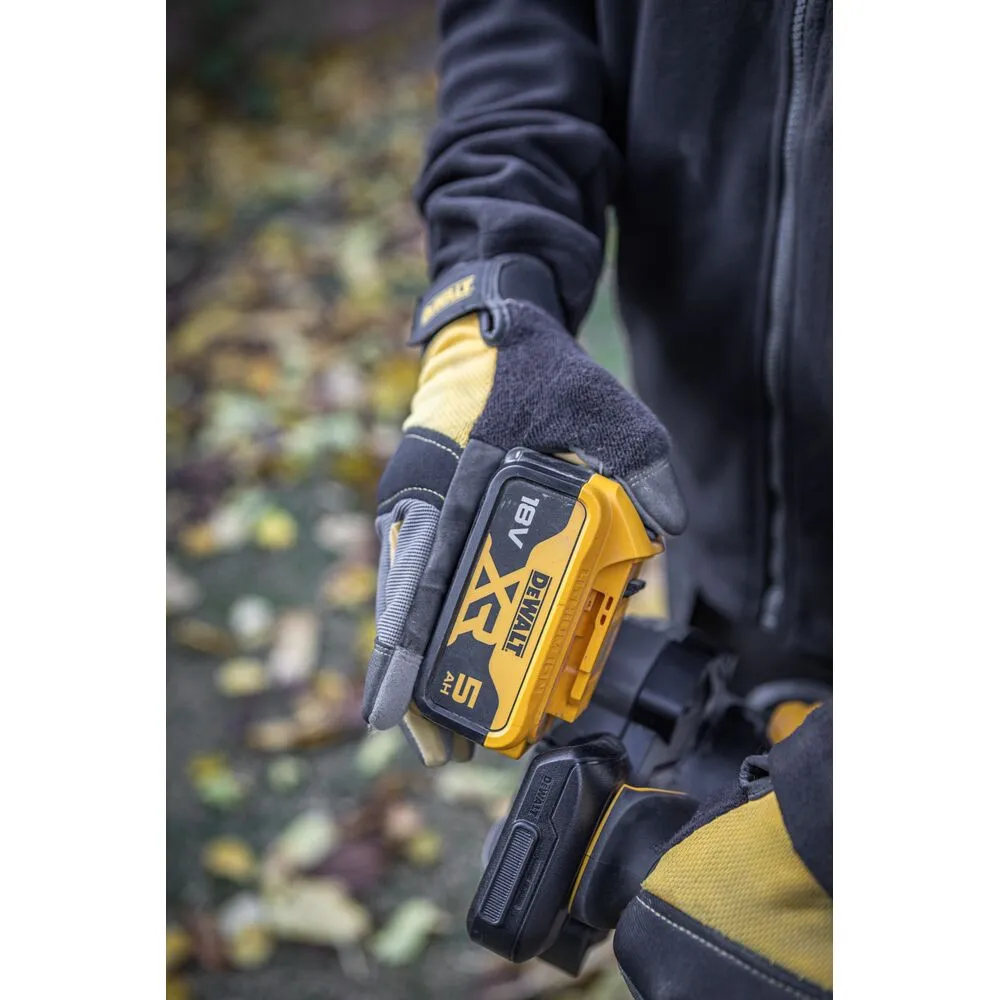 Pildil on näha DeWalt akutoitega lehepuhur DCMBL562P1, mida inimene kasutab kivist sillutise peal, et puhuda lehti.