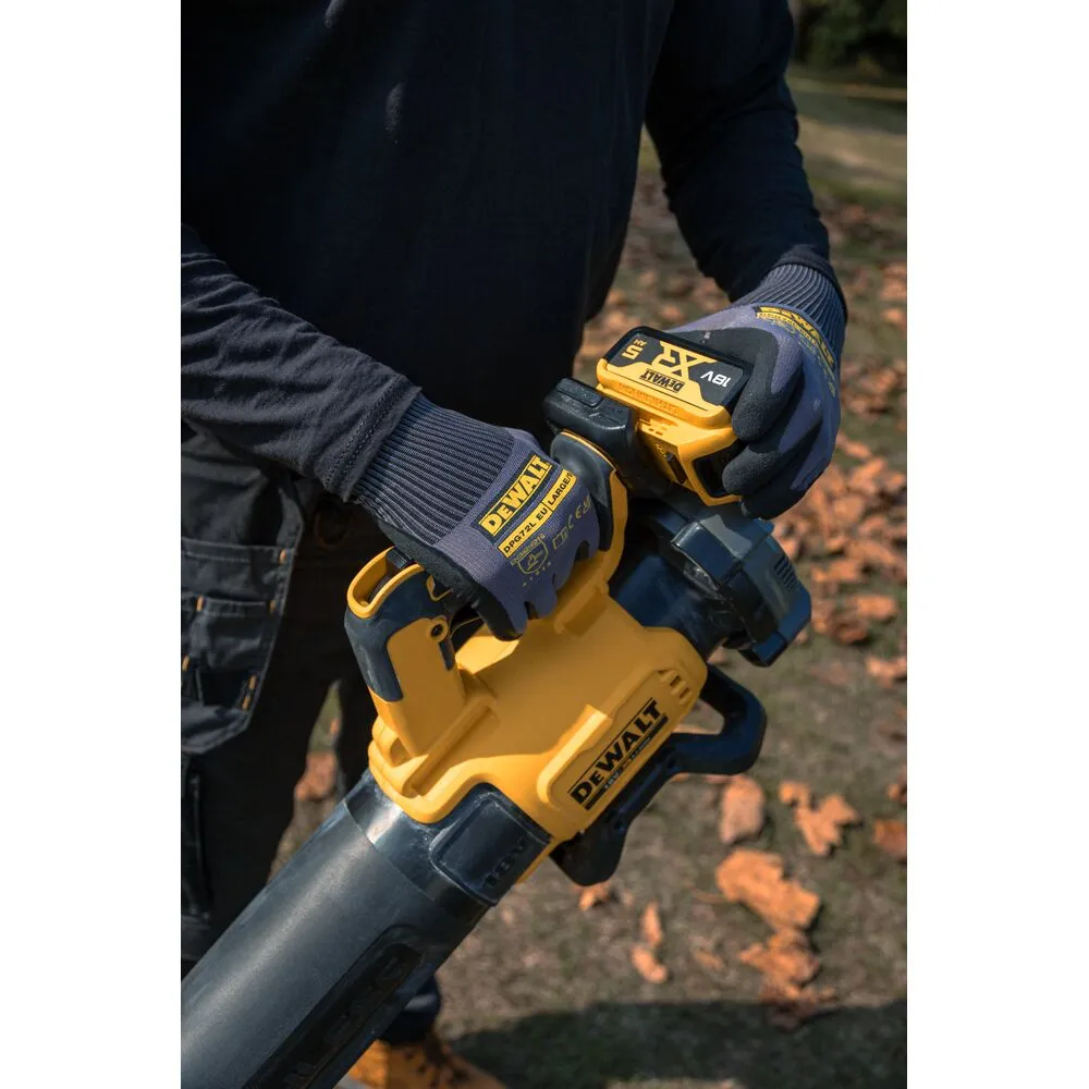 Pildil on DeWalt akutoitega lehepuhuri käepide, mida hoiab töömees kindaga, samal ajal kui taevas paistab läbi langenud...