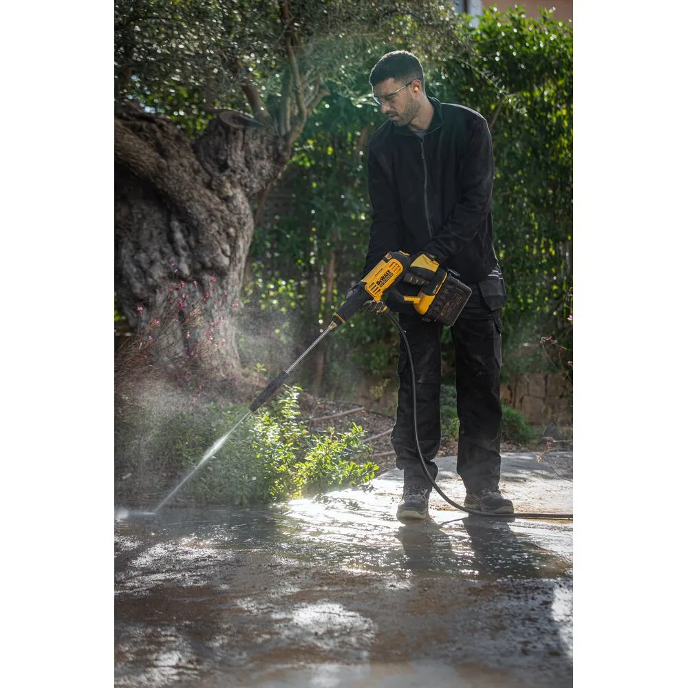 Pildil on mees, kes kasutab DeWalt akusurvepesurit DCMPW1000N, et puhastada kõnniteed.