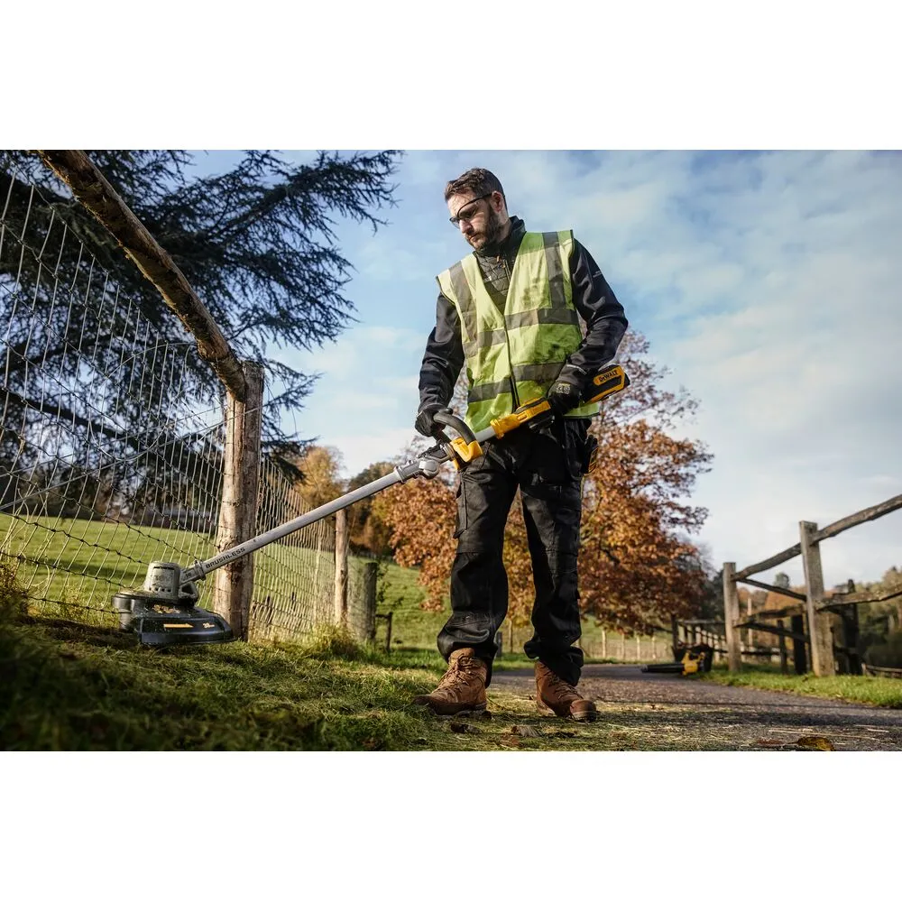 Pildil näeb inimene kandmas kindaid, kes hoiab DeWalt DCMST561P1 akutrimmerit.