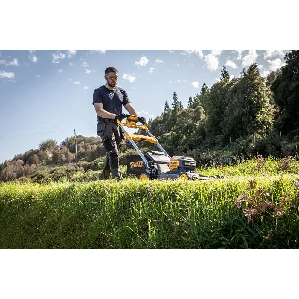 Pildil on mees, kes kasutab DeWalt akumuruniidukit DCMWSP660N muru niitmiseks suurel muruväljal.