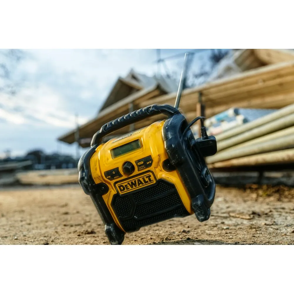 Pildil on näha DeWalt DCR020 raadio, mis on asetatud torusid täis hunnikule ehitusplatsil.
