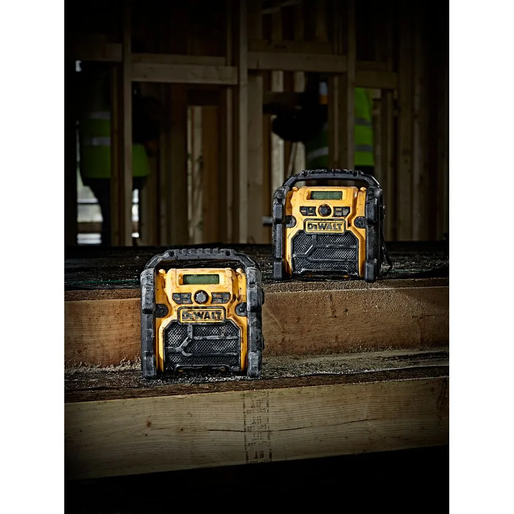 Pildil on DeWalt DCR020 raadio, mis on ehitusplatsil maapinnal.