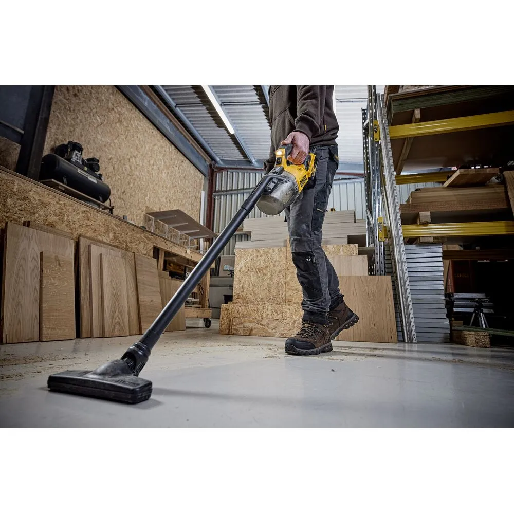Pildil on näha töömees, kes kasutab töökojas Dewalt akutolmuimejat DCV501LN, et koristada põrandat.