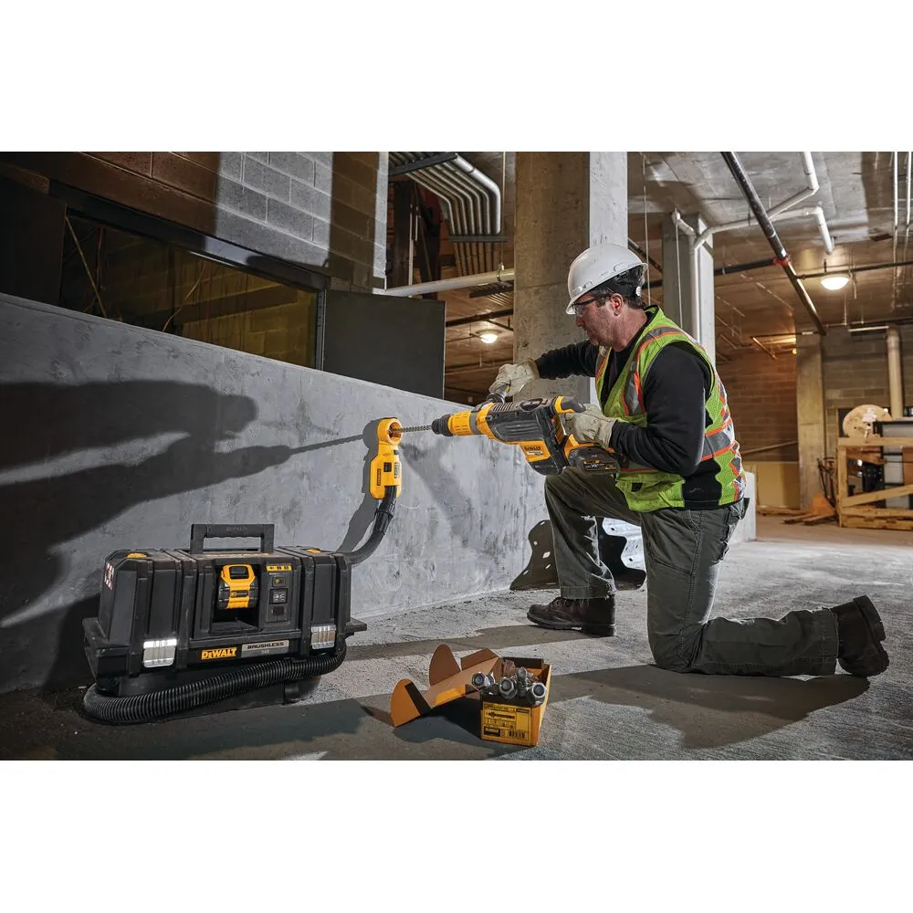 Pildil on mees kasutamas Dewalt akuga vee- ja tolmuimejat Flexvolt DCV586MT2, et koristada ehitusprahti seinast.