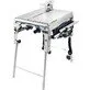 Pildil on Festool lauasaag PRECISIO CS 70 EG, mis on paigaldatud valgele metallist alusele ja millel on saeketas...