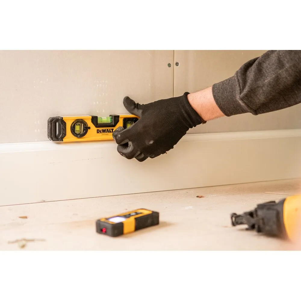 Pildil on DeWalt vesilood 25 cm, millega inimene kontrollib seinapaneeli loodimist.