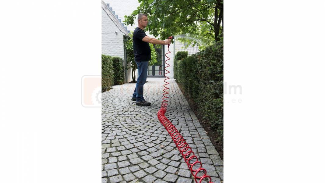 Pildil on mees, kes hoiab käes punast Kreator 15 m kastmisvoolikut, mis on keritud mööda kivisillutist.