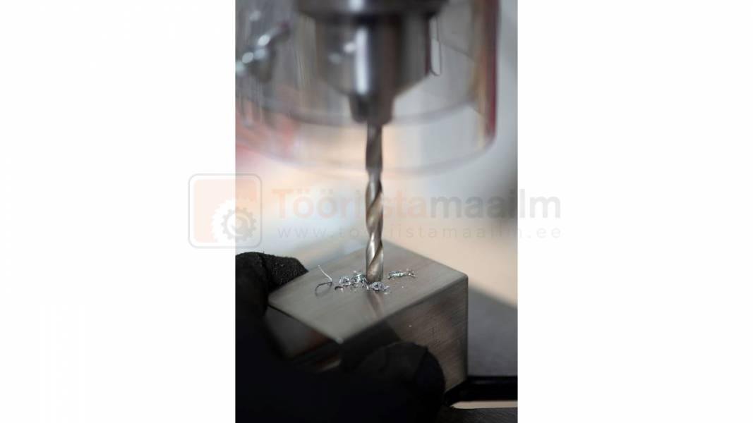 Pildil on näha, kuidas Powerplus X POWX153 puurpink puurib metallist kuubikusse auke.