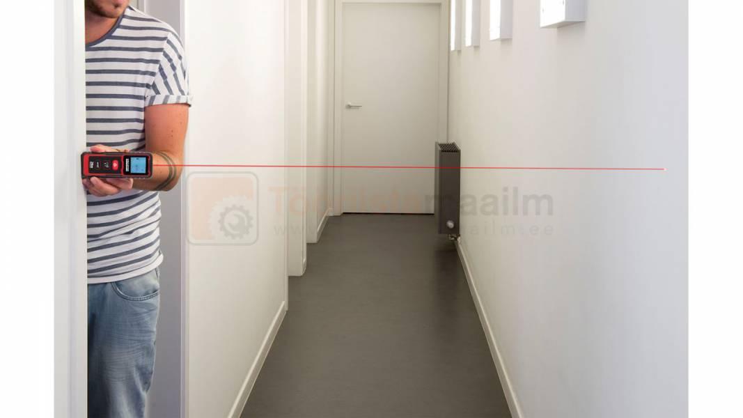 Pildil on mees, kes kasutab Kreator KRT706500 laserkaugusmõõtjat, et mõõta koridori pikkust.