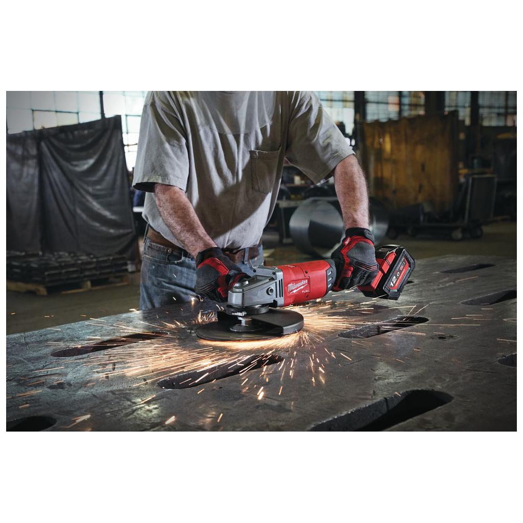 Pildil on mees, kes kasutab Milwaukee akunurklihvija M18 FLAG230XPDB-0C, tekitades sädemeid metallpinnal.