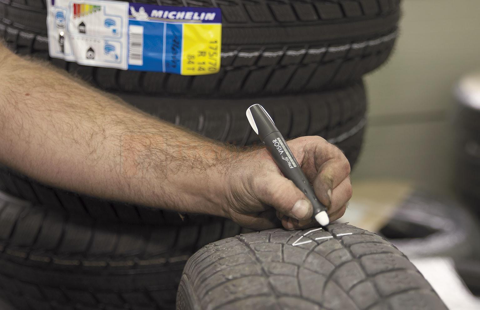 Pildil on näha, kuidas mees kasutab markerit PICA Visor permanent, et märgistada rehvi mustrit.