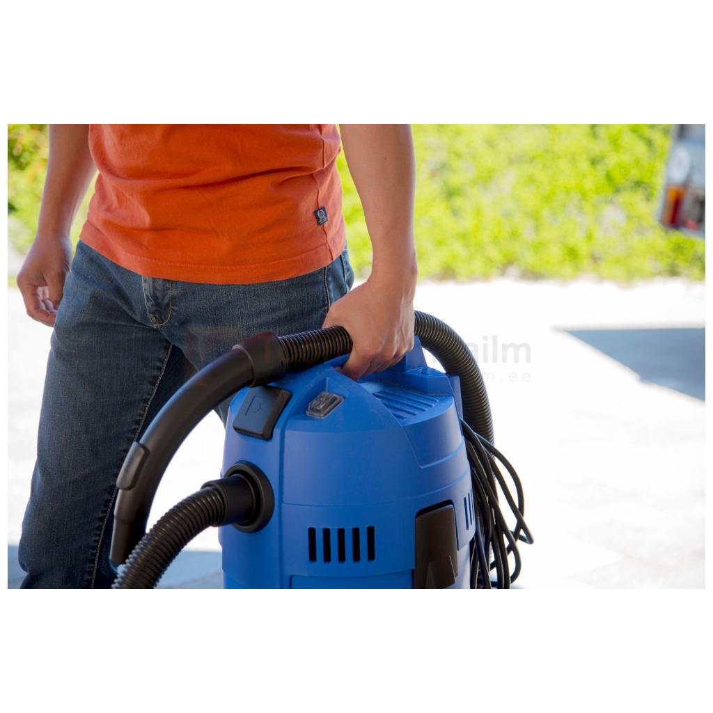 Pildil on inimene, kes hoiab käes sinist Nilfisk Buddy II 18 vee- ja tolmuimejat.